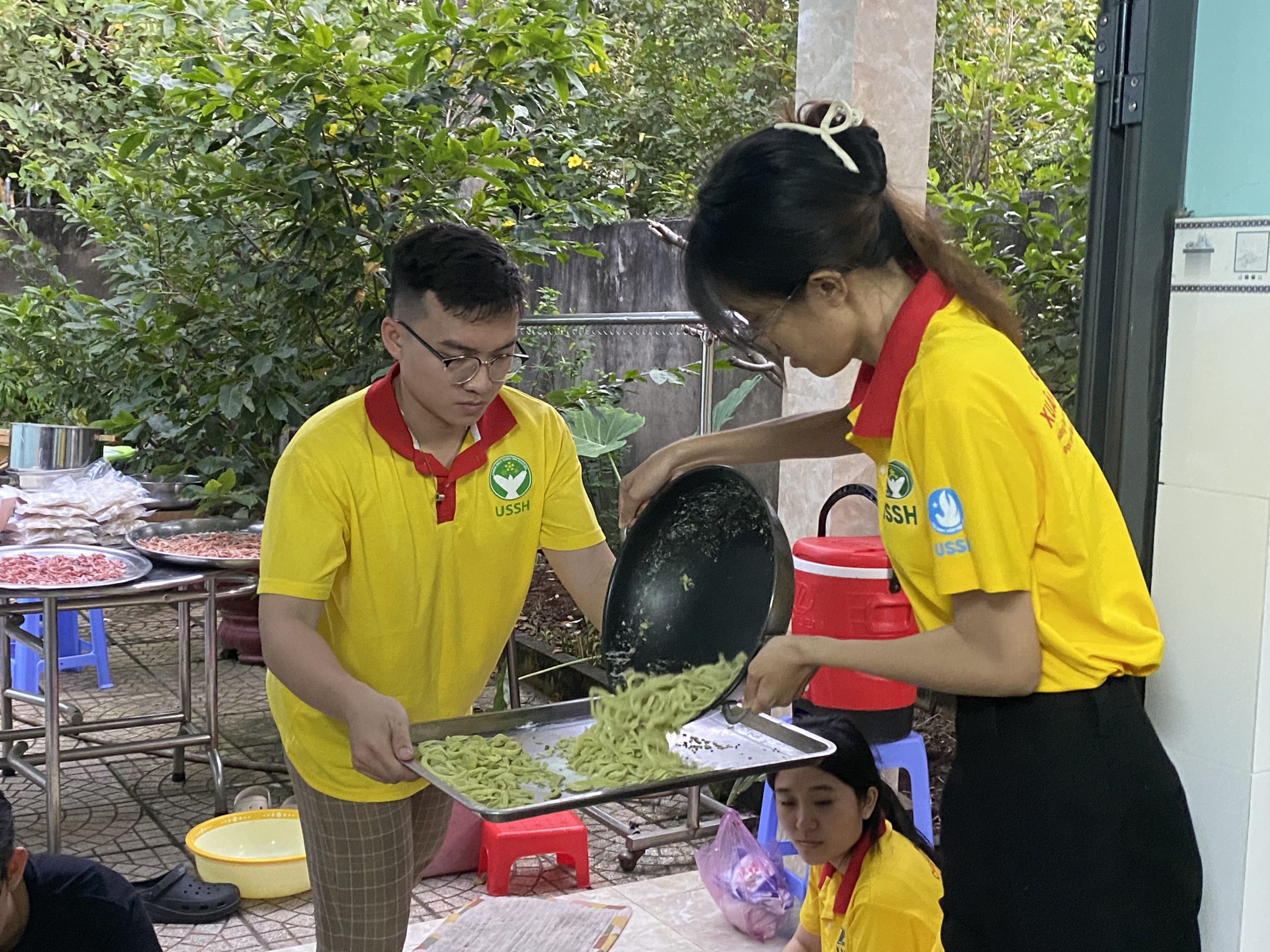 Ảnh 3. Nhật Vy (đứng bên phải) và các thành viên trong CLB Tình nguyện IR4C quây quần nấu mứt dừa để làm quà Tết cho người dân địa phương (Ảnh: NVCC)