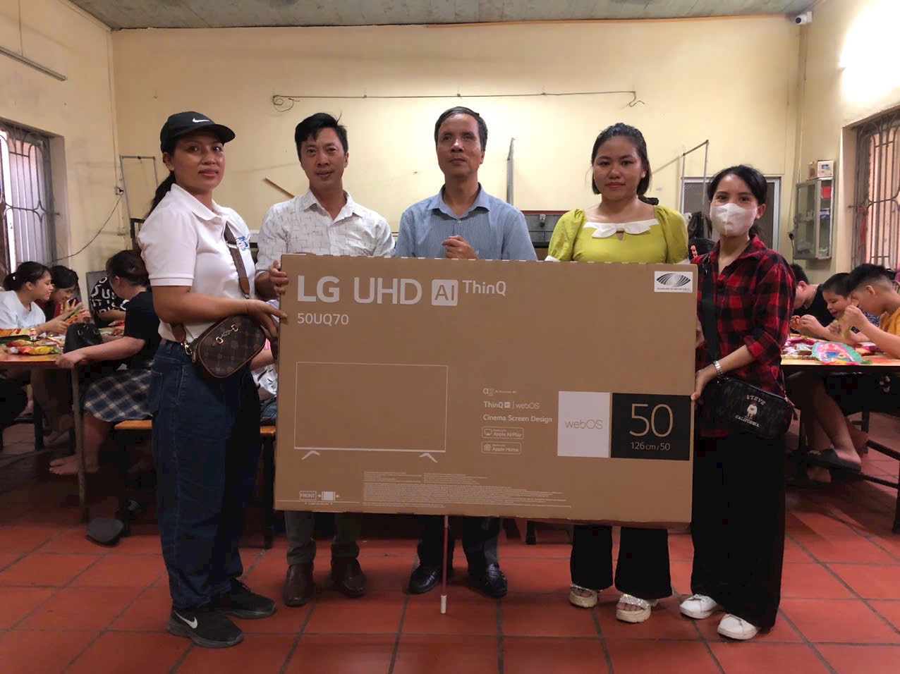 Ảnh 3: Chị Thắm ( áo đỏ) cùng các mạnh thường quân trao tặng chiếc TV cho lớp trẻ em bị khiếm thị.